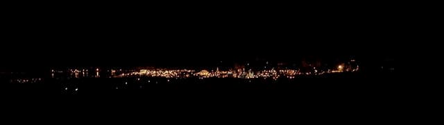 Refinería de BP en Grangemouth vista de noche desde la distancia, con la hilera de luces naranjas del recinto industrial recortada sobre el horizonte escocés